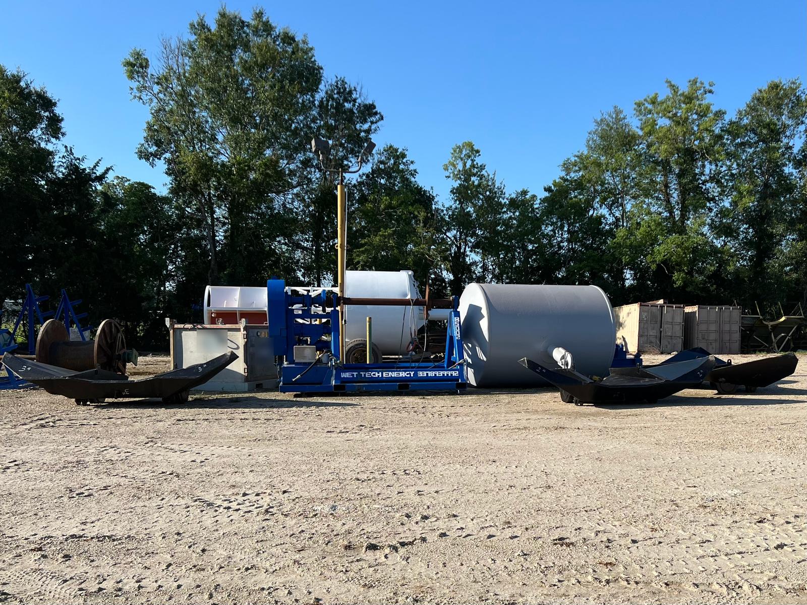 Anchors, the Wet Tech RS-002 spooling unit, a grey steel mooring buoy and a white smart buoy staged in the Wet Tech yard