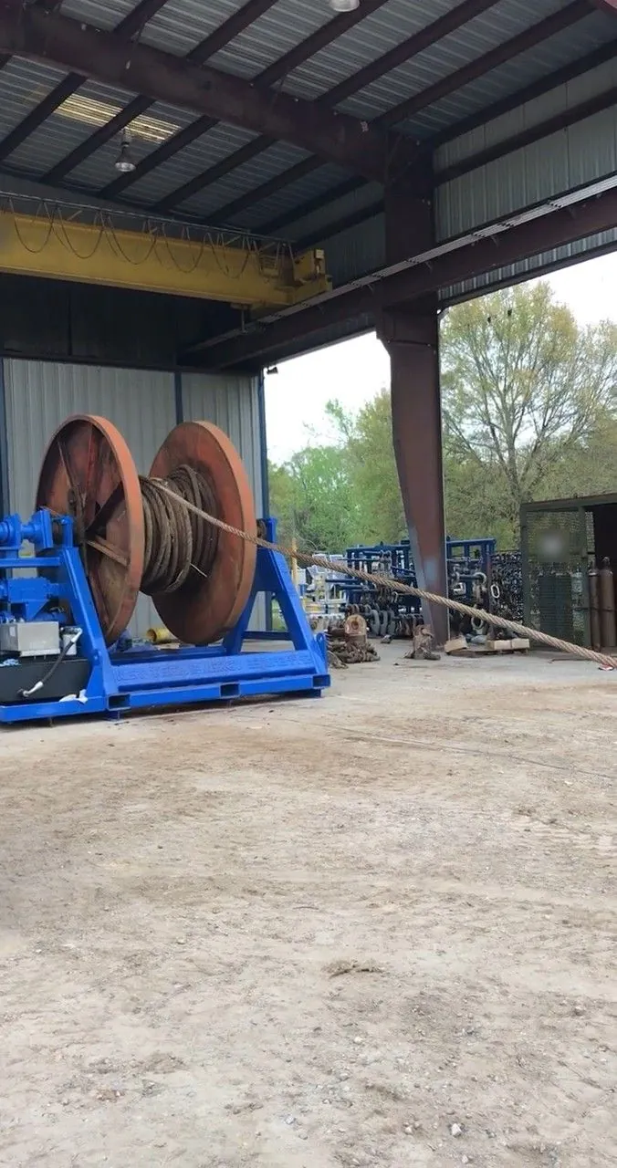 Wet Tech RS-002 spooling unit with a rust-red steel reel of wire rope inside the covered Wet Tech fab shop