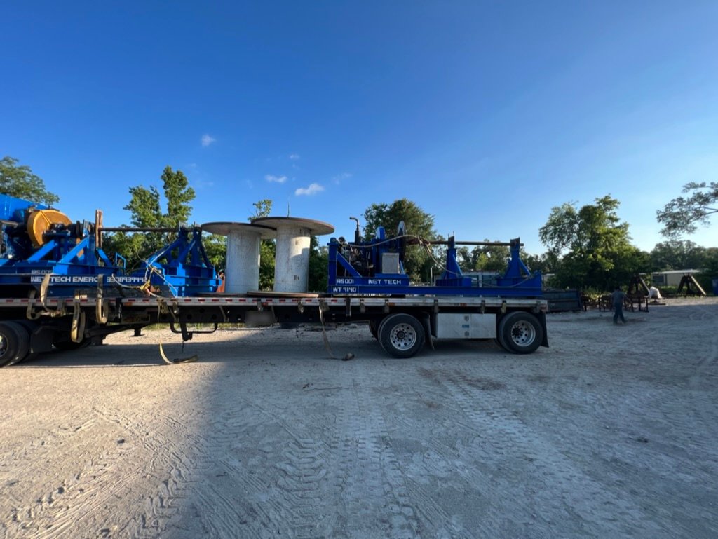 Wet Tech RS-005 and RS-002 wire rope spooling units with steel reels on a flatbed trailer